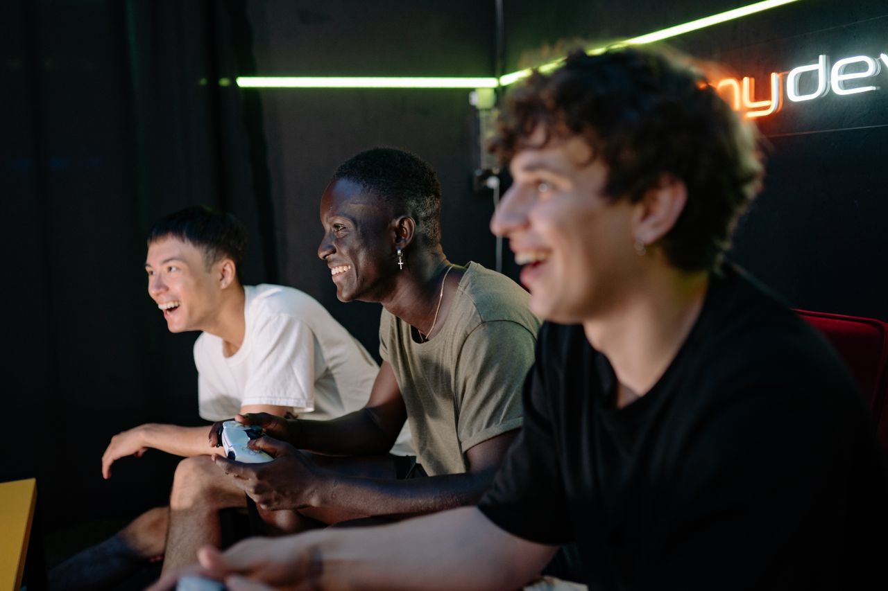 Crafting Captivating Headlines: Your awesome post title goes here Three diverse young men playing video games indoors, showing excitement and enjoyment.